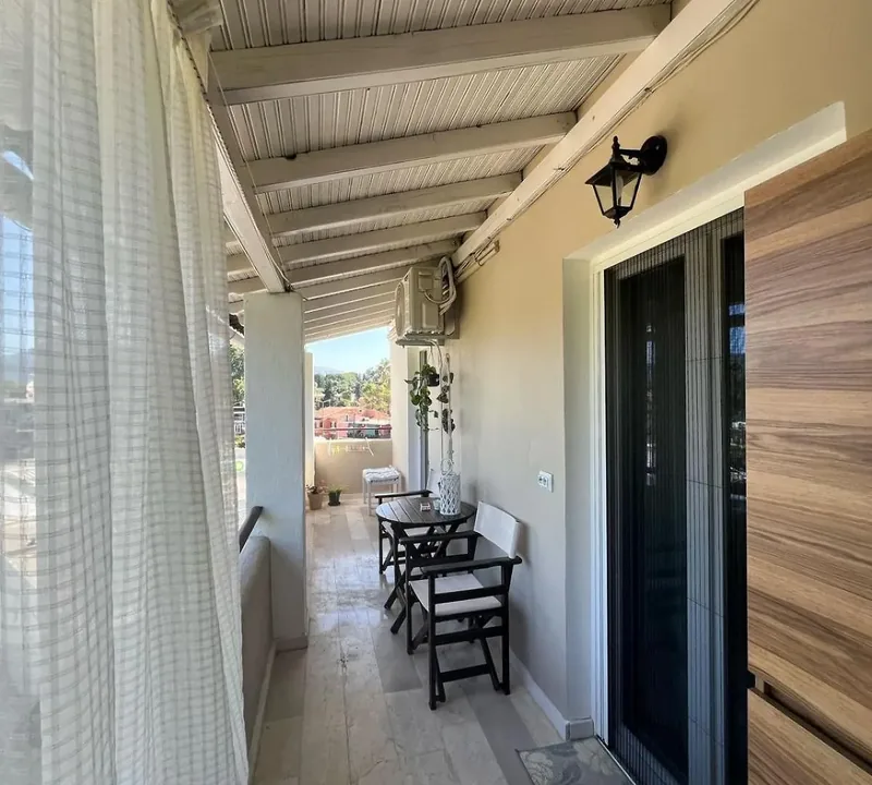 Long covered terrace at Eda House with seating and a wooden apartment door