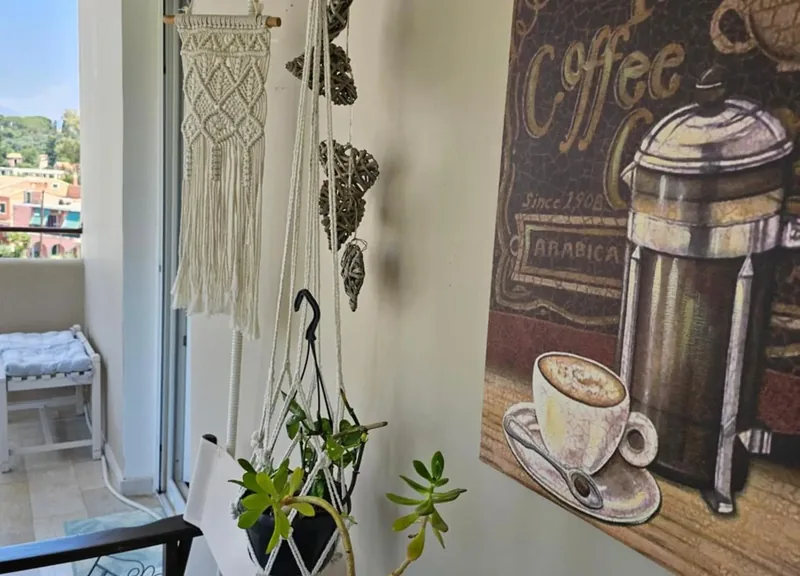 Balcony corner at Eda House with a macramé hanging, plants and coffee wall art