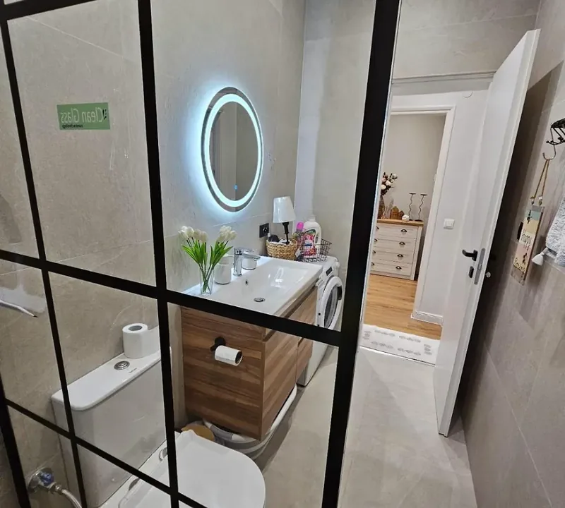 Bathroom at Eda House with backlit round mirror, WC and vanity unit